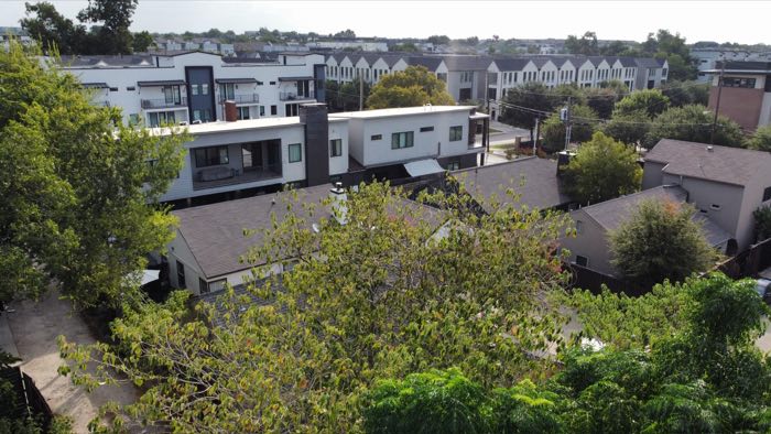 Aerial showing rows of newly built modern townhomes immediately beyond the alley from the site.